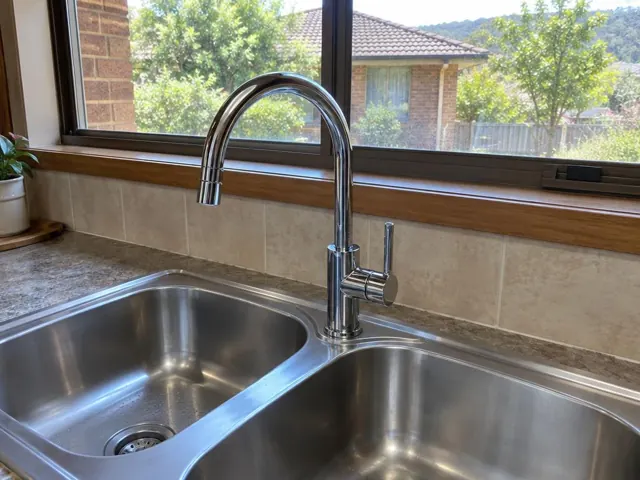 Chrome kitchen mixer tap over a double sink beside a tiled splashback and window in Macquarie Hills